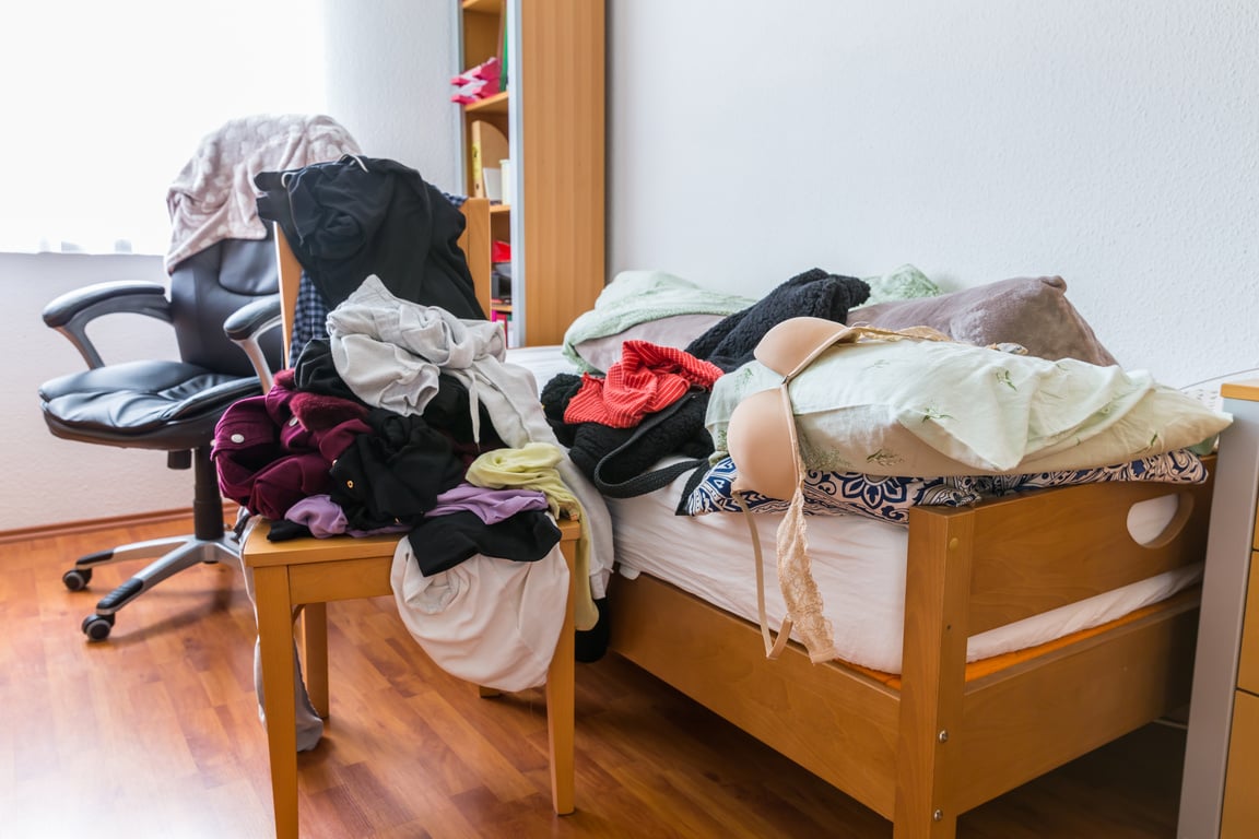 Messy teenager room. Untidy cluttered bed,  dirty clothes.